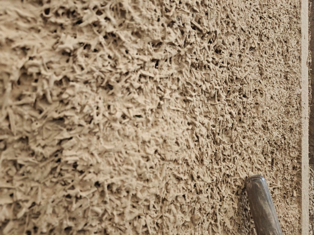 Enduit terre-paille lissé à la taloche — texture fibreuse d'une isolation biosourcée
